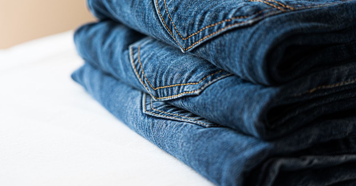 Stack of neatly folded blue denim jeans highlighting stitching details.