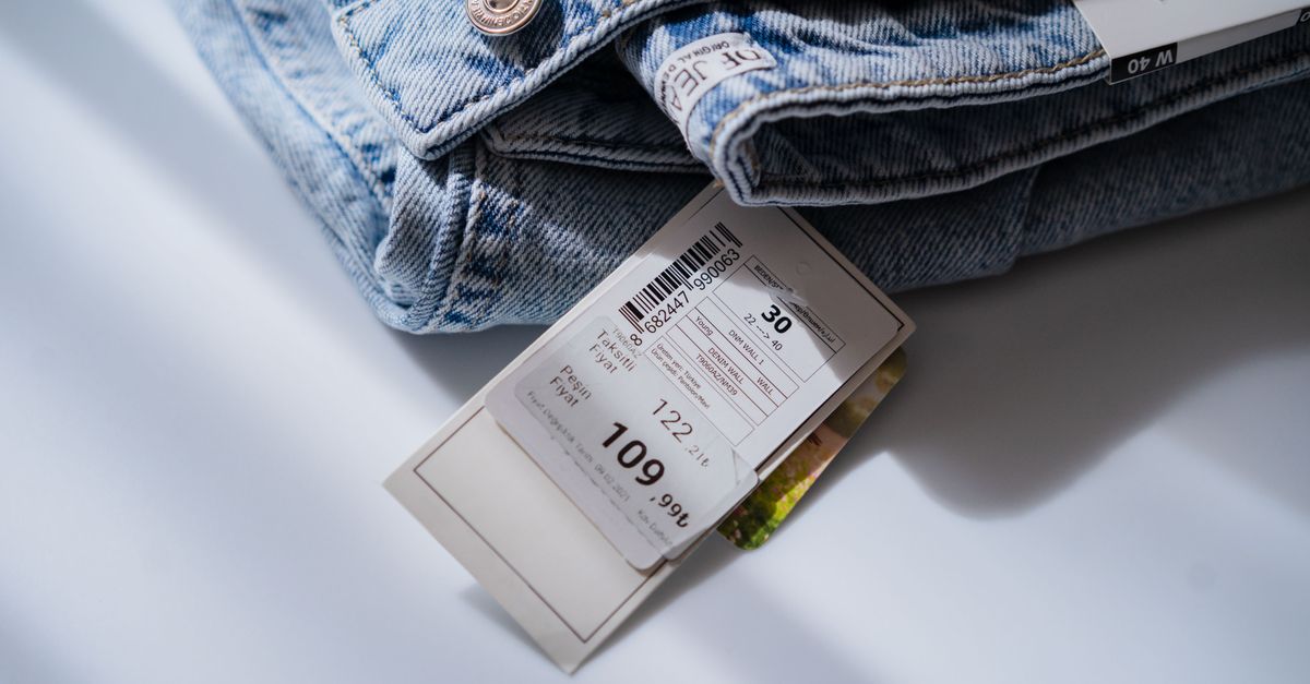 From above of blue jeans with retail price and size label placed on white table