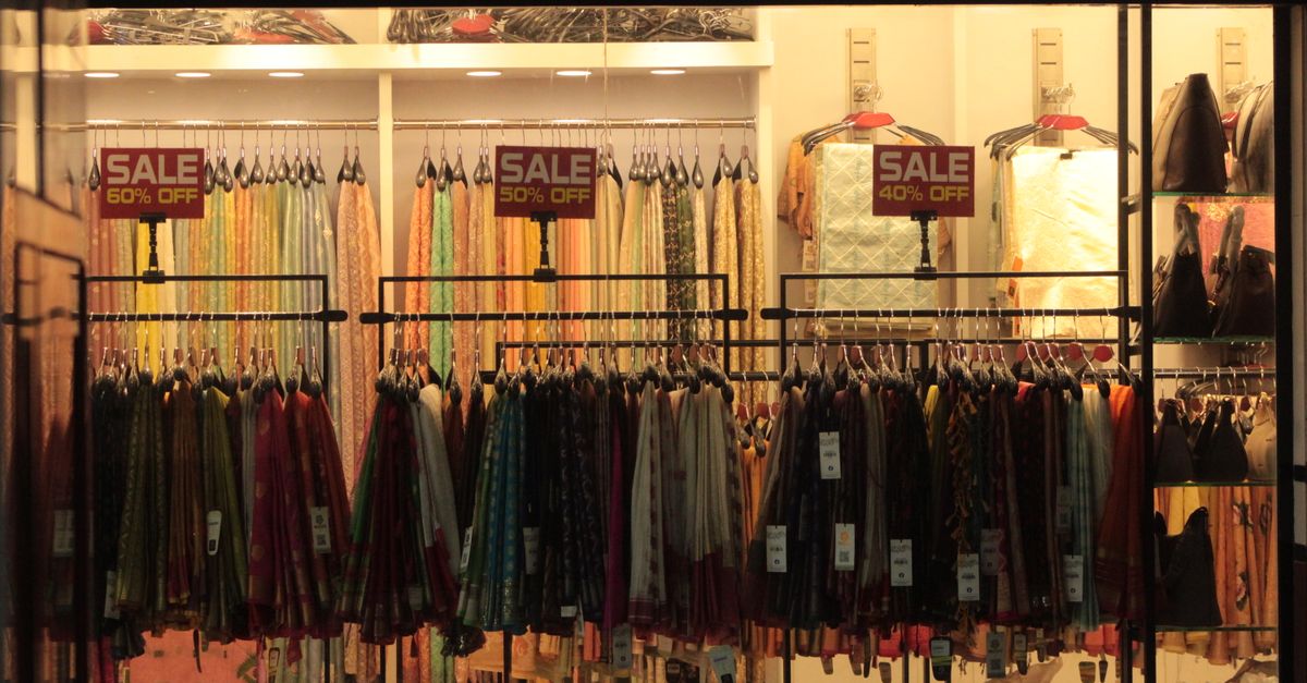 Vibrant clothing store interior showcasing colorful fabrics with sale discount signs.