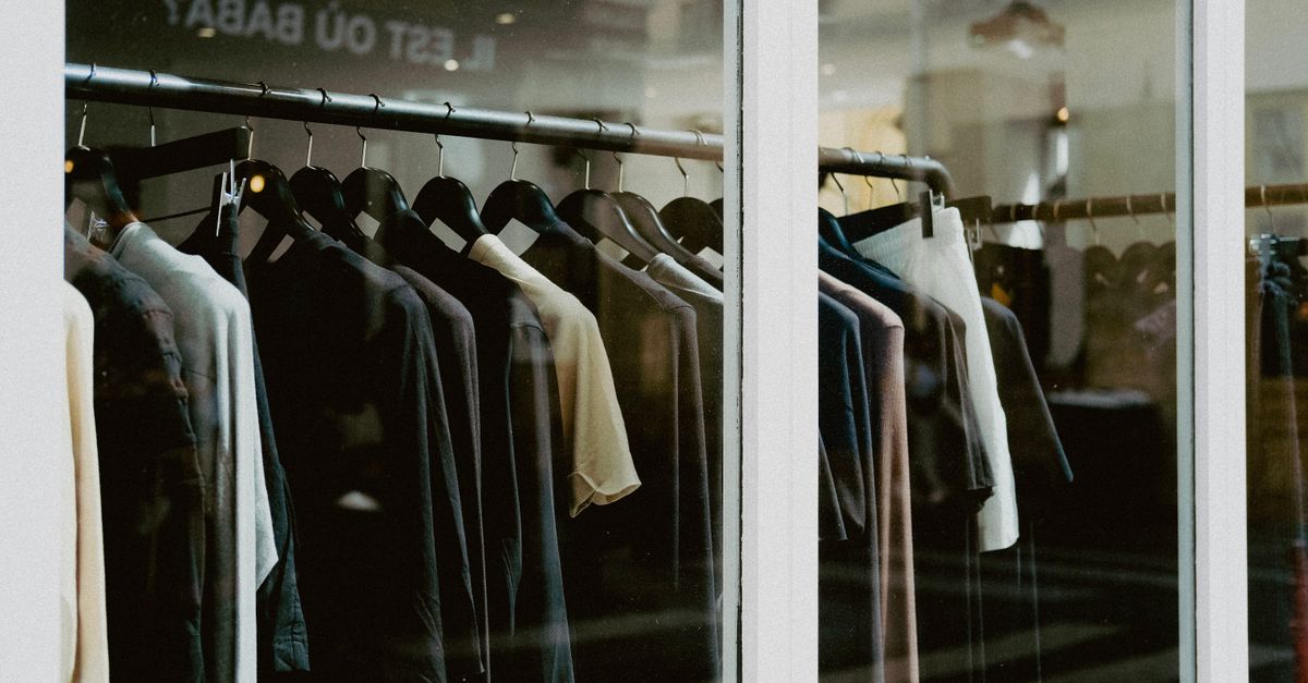 Close-up of clothing on hangers inside a fashion store window.