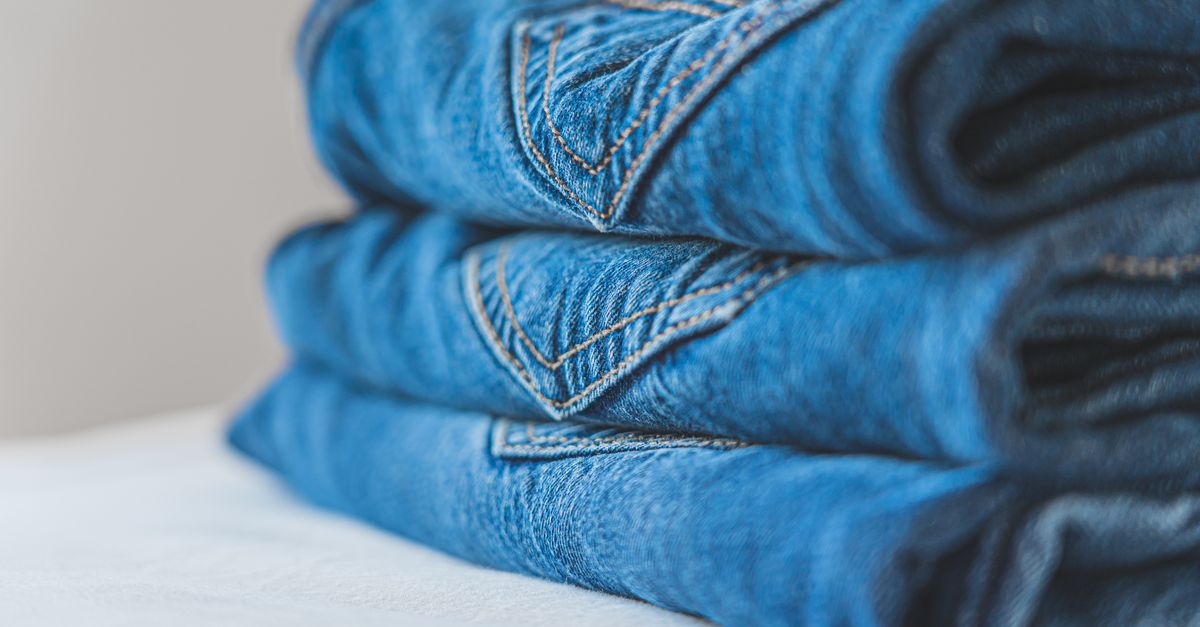 Close-up of neatly folded blue denim jeans on a white surface.