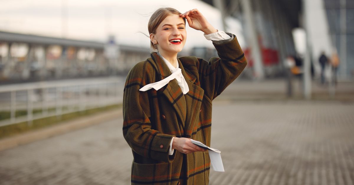 A happy woman in a plaid coat smiling outdoors, exuding warmth and style.